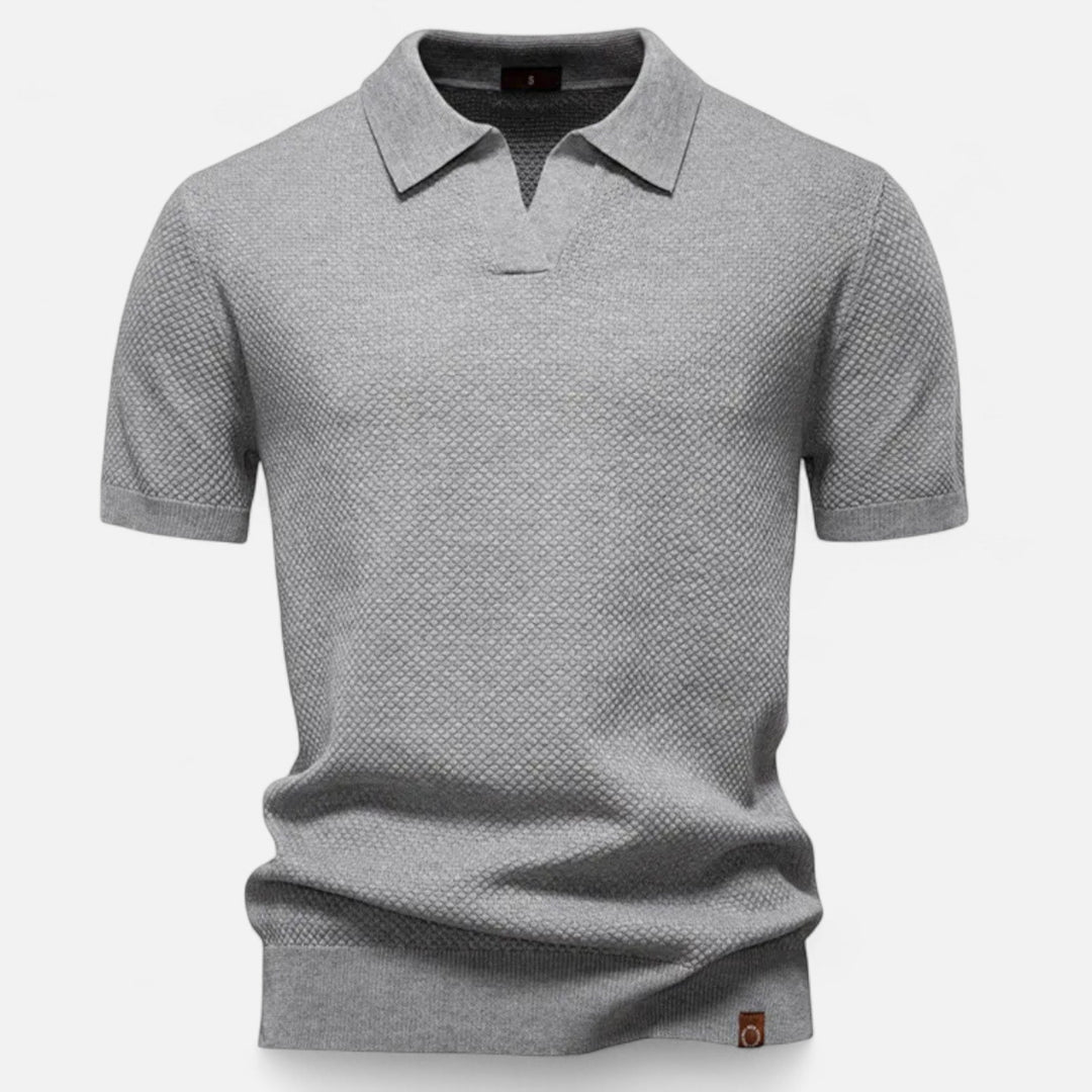 A man wearing a refined style wool polo shirt featuring a classic pineapple motif.