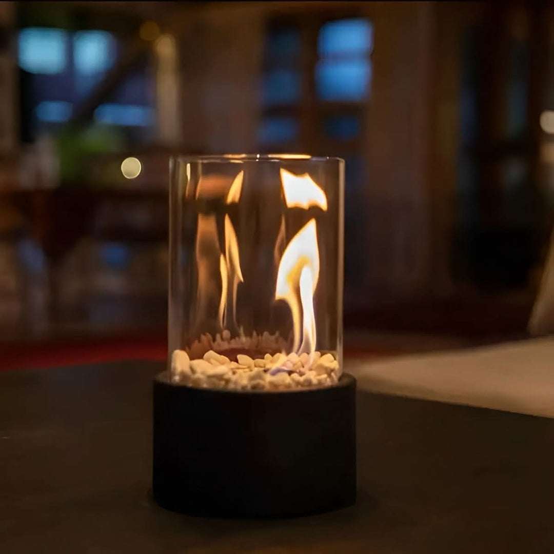 Modern bioethanol table fireplace with glass & metal base for indoor & outdoor ambiance.