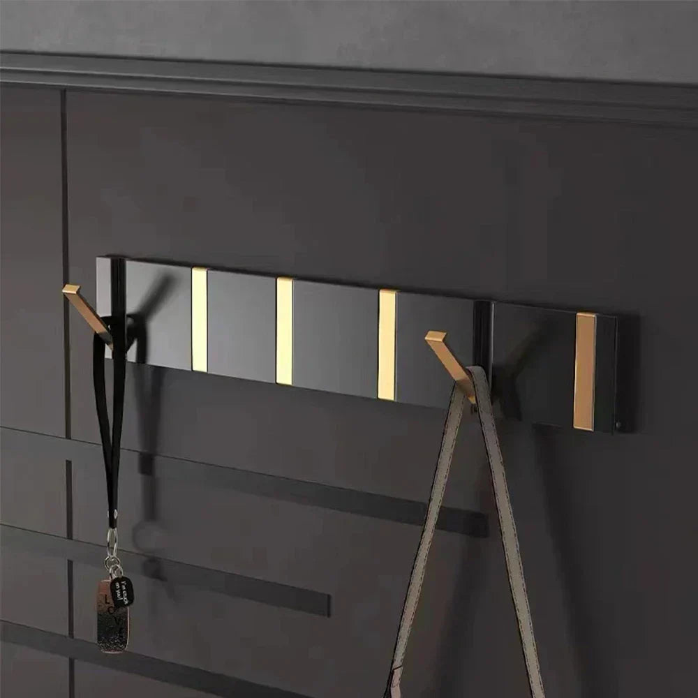 Minimalist foldable wall hook in black & gold, ideal for coats and towels. Modern design.
