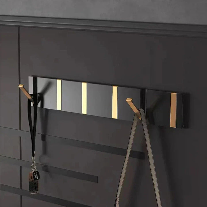 Minimalist foldable wall hook in black & gold, ideal for coats and towels. Modern design.