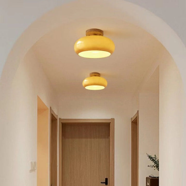 Elegant modern flush ceiling light featuring a sleek wood base & glass shade for dining rooms.