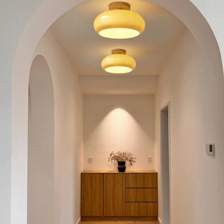 Modern flush mount ceiling light with a wood finish and glass shade, ideal for home interior lighting.