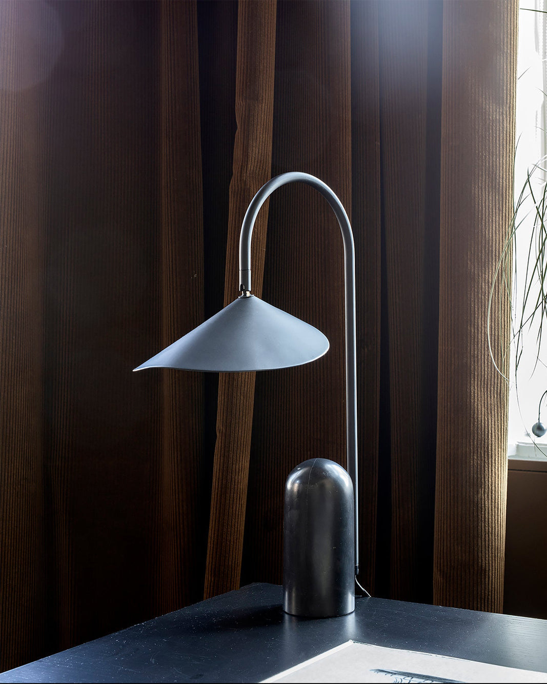 Sculptural black lamp, arched, with a contemporary feel & a heavy marble base.