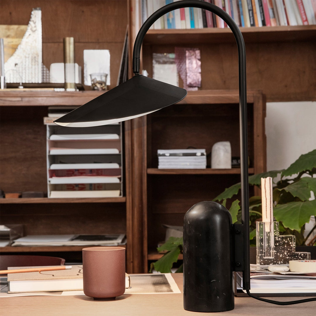 Japandi table lamp, black, arched, minimalist, and supported by a marble base.