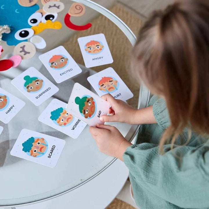 Toddler plays with a Montessori facial expression toy, learning about emotions and early speech development.