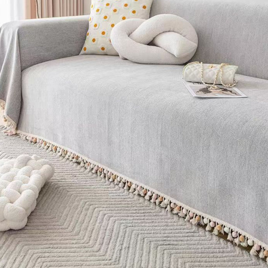 Pet friendly herringbone sofa cover with tassel fringe for boho living room decor. Protects furniture.