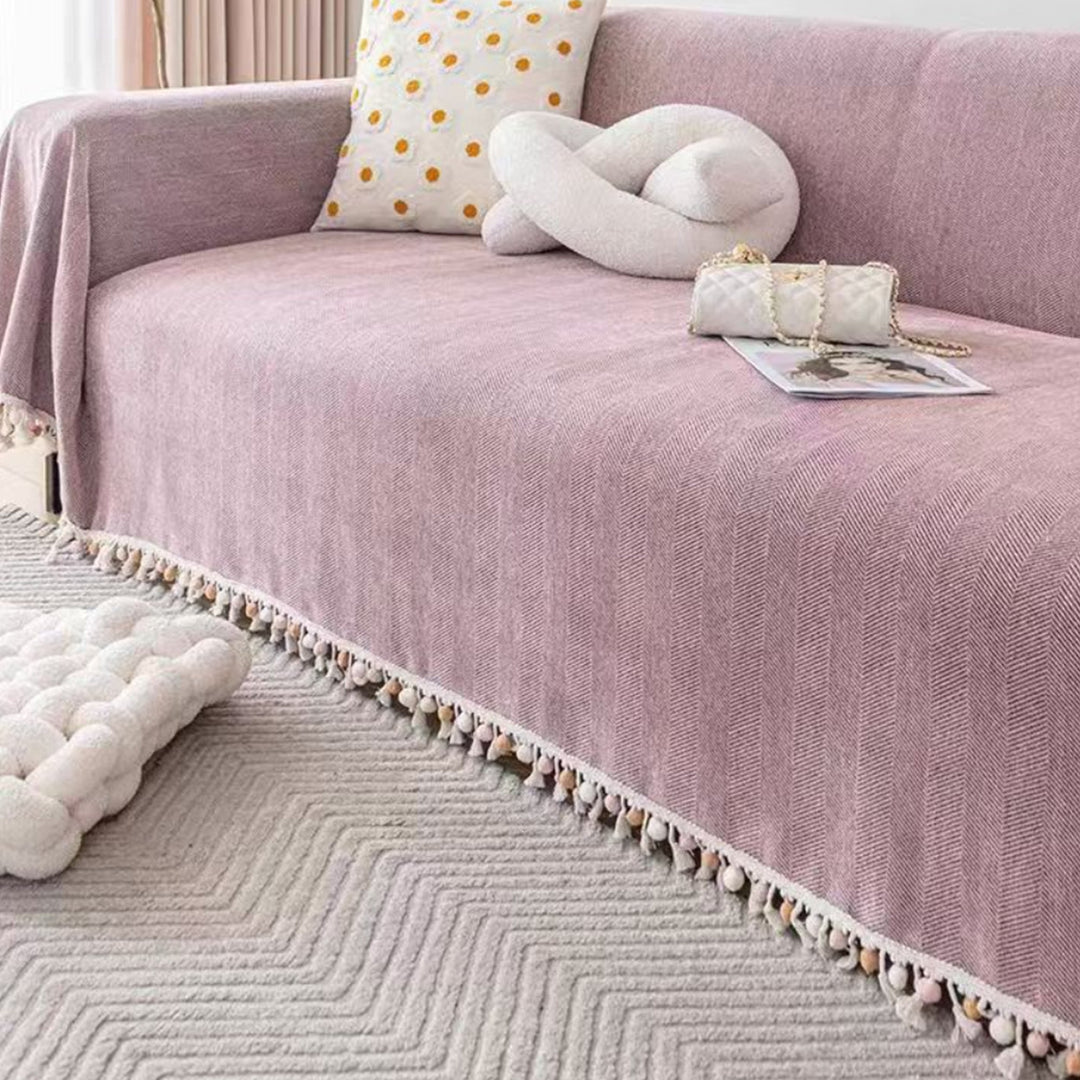 Close-up of a pet friendly herringbone sofa cover, showcasing the woven texture & tassel fringe, ideal for boho homes.