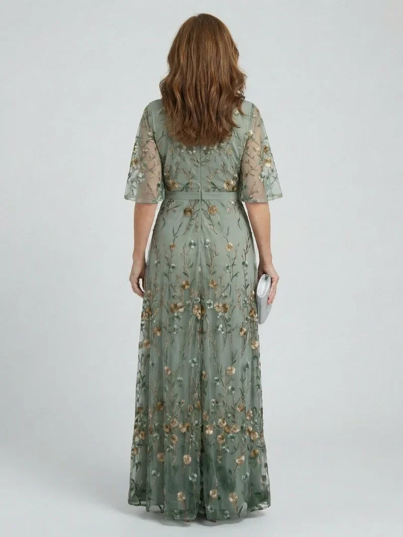 Flowy sage green maxi occasion dress for women, featuring a flattering drop waist, v-neck, and delicate floral embroidery.