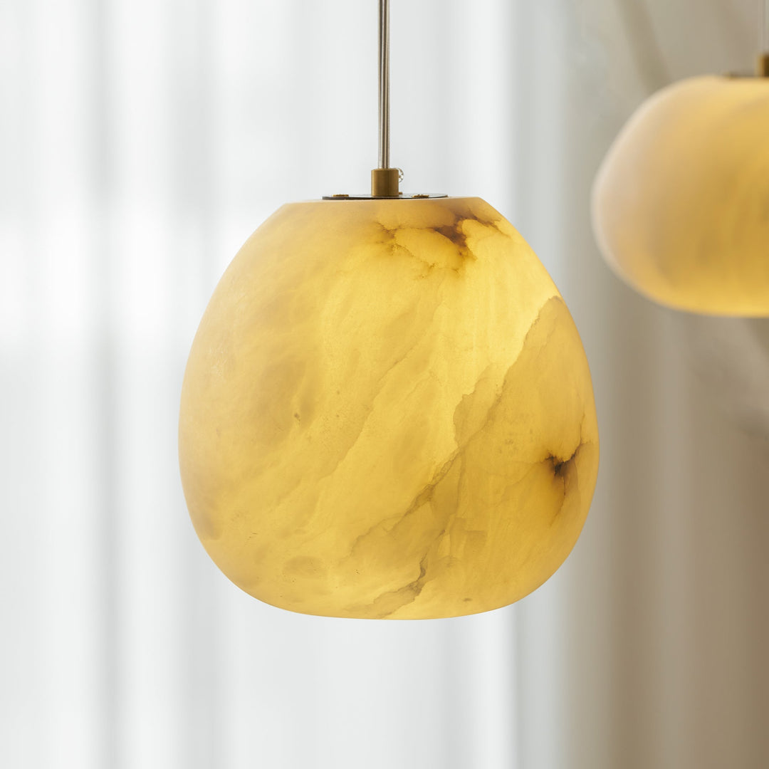 Modern pendant light, sculptural pebble design, brass finish, enhancing Japandi aesthetics.