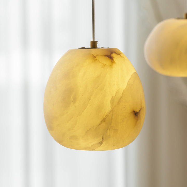 Modern pendant light, sculptural pebble design, brass finish, enhancing Japandi aesthetics.