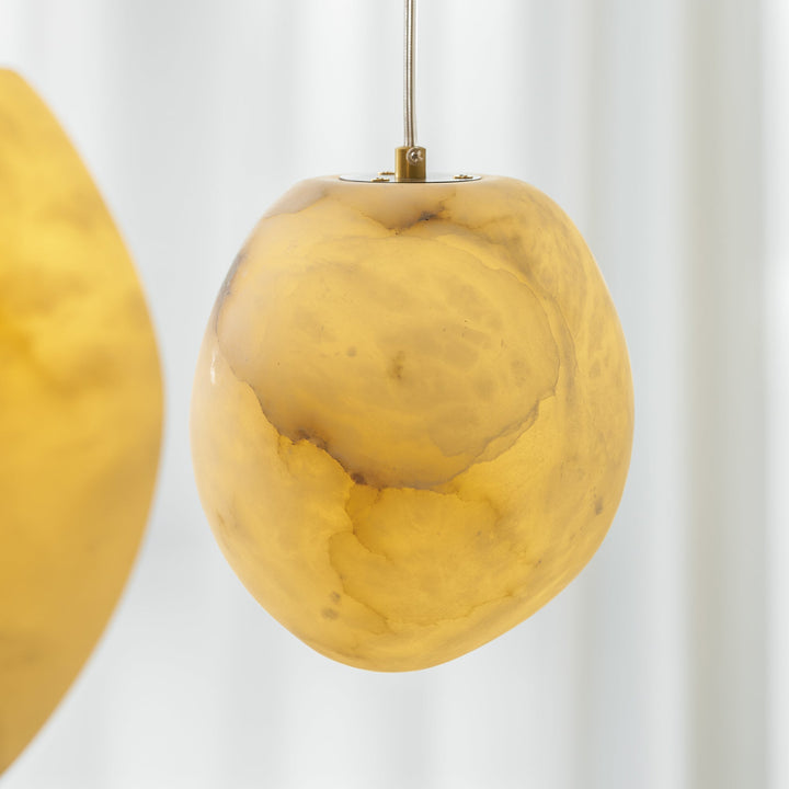 Ambient light for serene spaces: sculptural pebble pendant lamp with a brass finish.