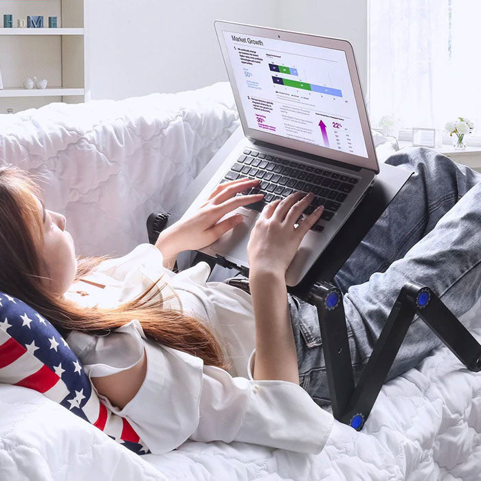 Silver adjustable ergonomic laptop stand for desk & bed, improving posture & productivity.