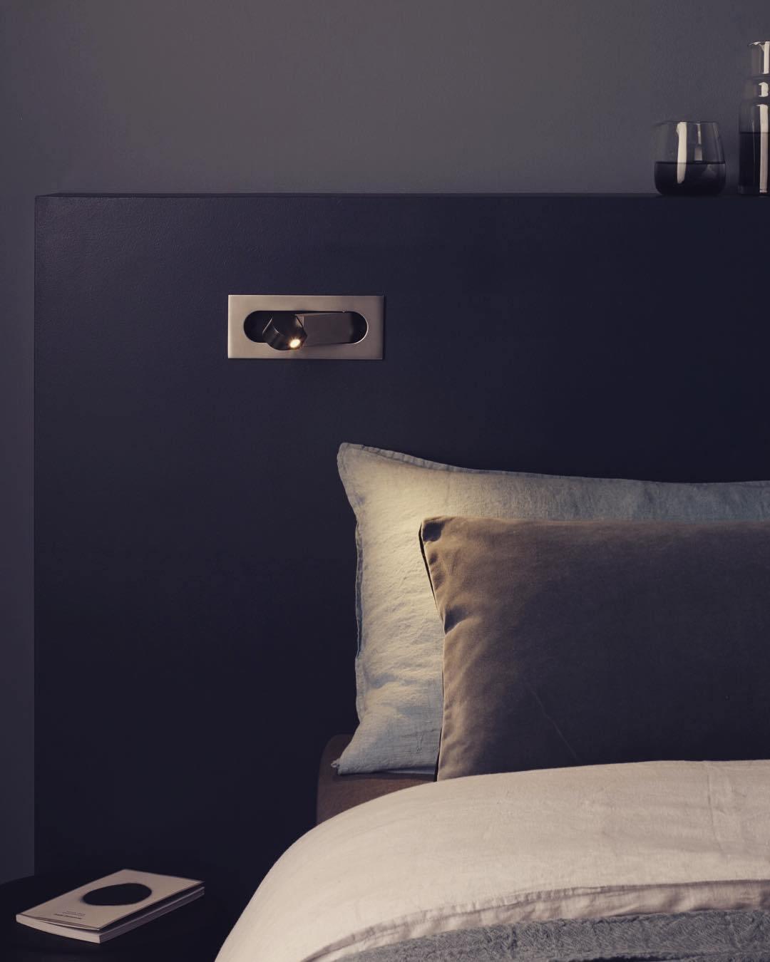 Contemporary LED wall light, adjustable, provides soft illumination for bedroom reading.