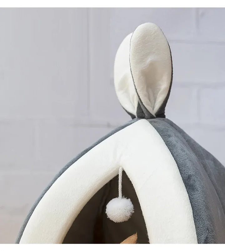 Plush gray cave cat bed, a cozy sanctuary with an integrated play ball for playful kittens.