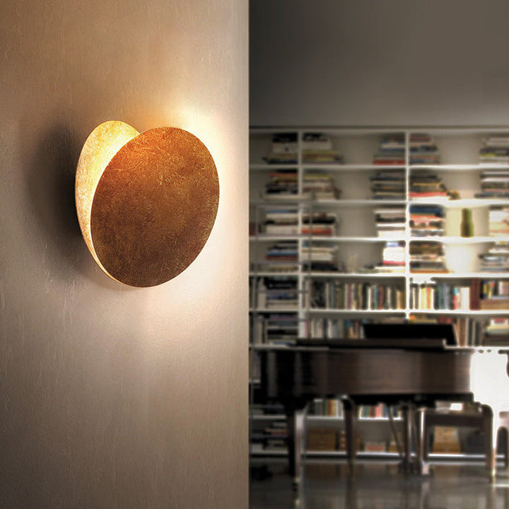 Contemporary metal LED wall sconce, round design. Emits warm white light for modern indoor living spaces.