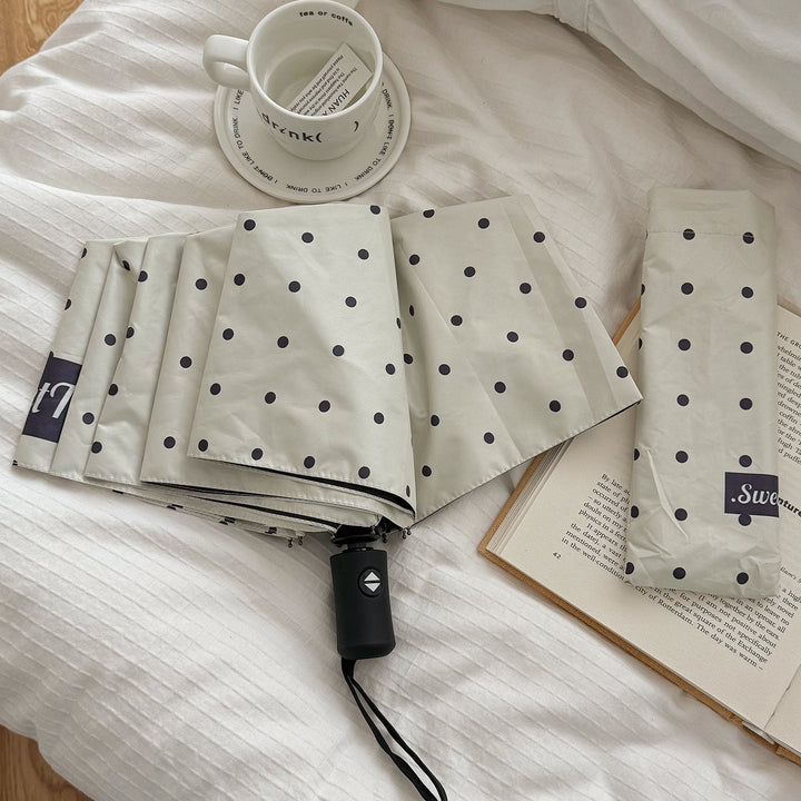 Ultra-compact folding umbrella for women, lightweight rain protection on the go.