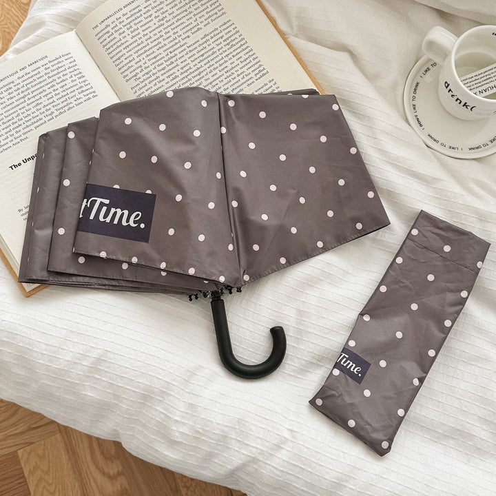 Polka dot portable umbrella for women, stylish and effective rain shield.