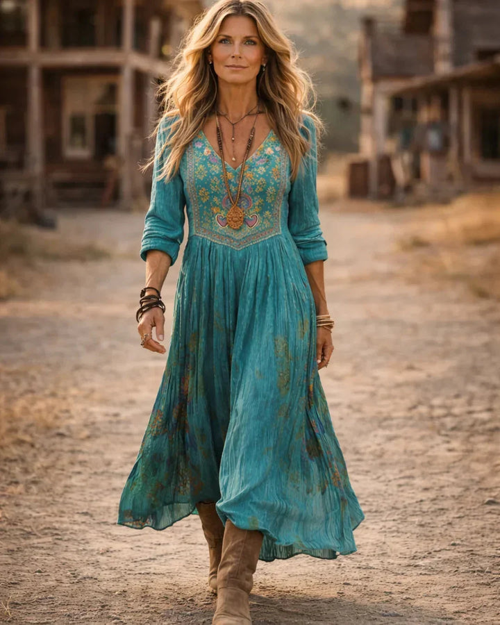 Women's flowy bohemian maxi dress in teal, featuring intricate embroidery, a flattering V-neck, and long sleeves.