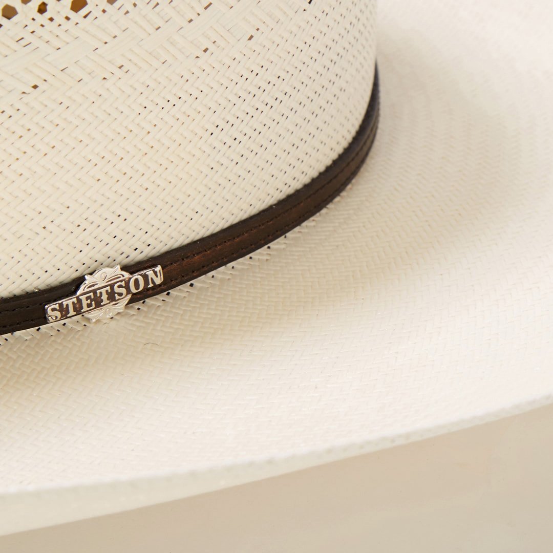 Close-up of a ventilated cowboy hat showing the intricate leather band & decorative silver conchos.