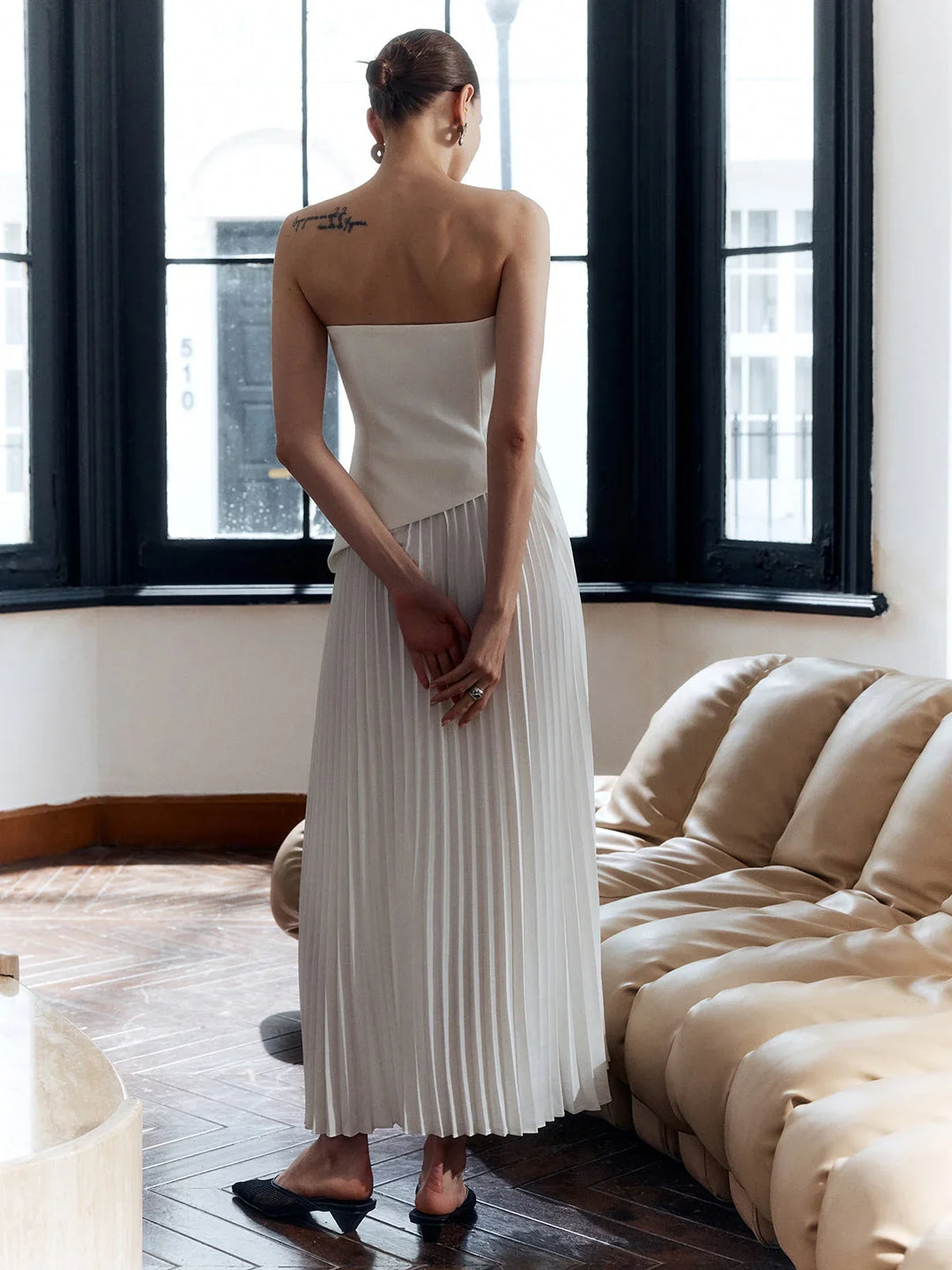 Strapless white pleated maxi dress featuring a chic asymmetric hem for women's formal events.