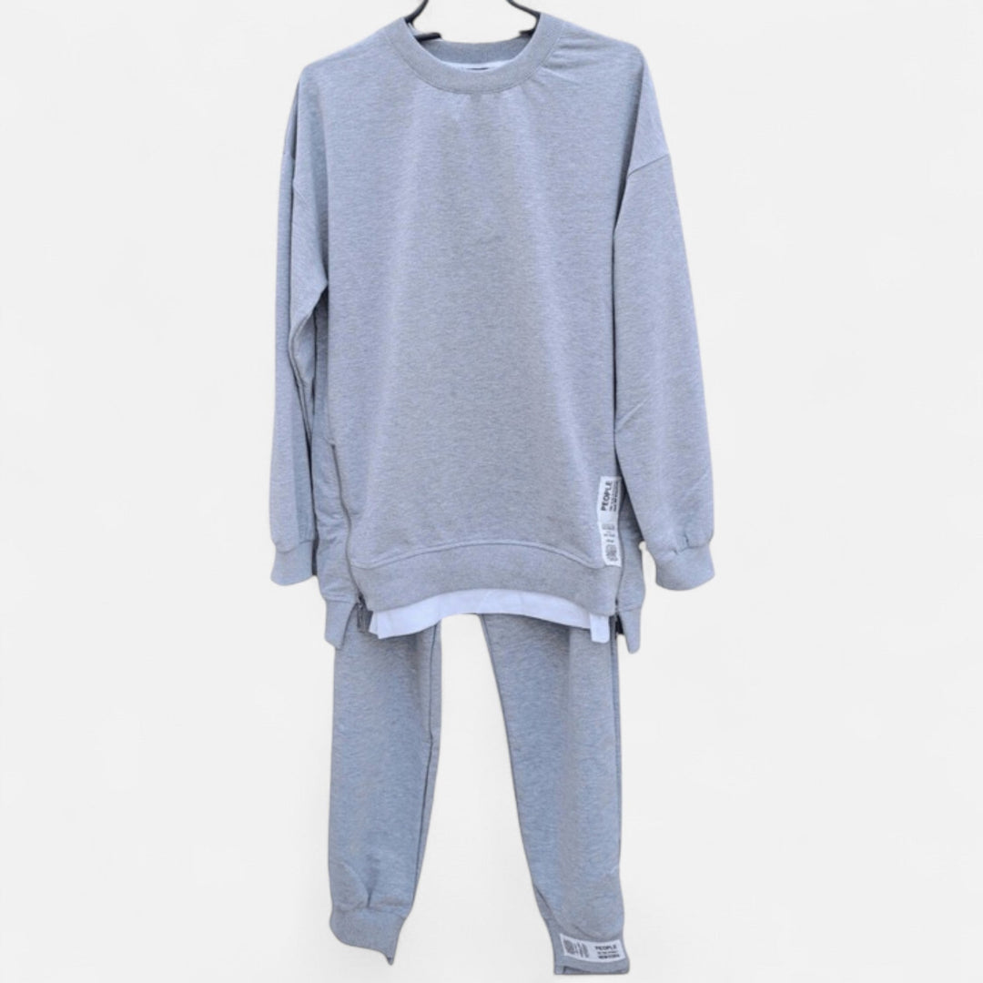 Woman wearing chic two-piece set: slit sweatshirt & slim pants. Comfortable, elegant loungewear for everyday style.