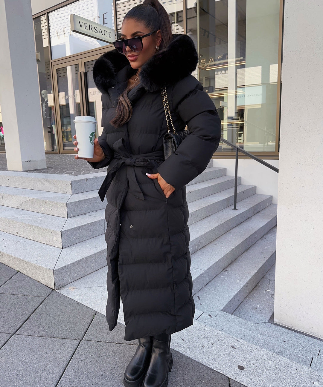 Warm women's black maxi length puffer jacket with belt, ideal for winter outerwear.