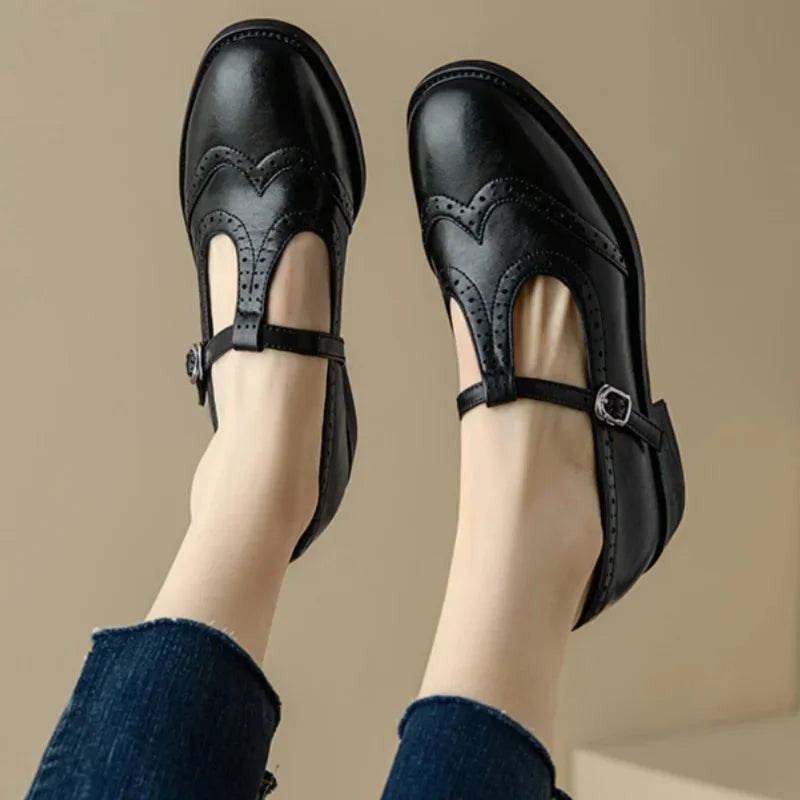 Close-up of black Brogue T-Strap Mary Jane shoes, showcasing decorative perforations and secure buckle closure.