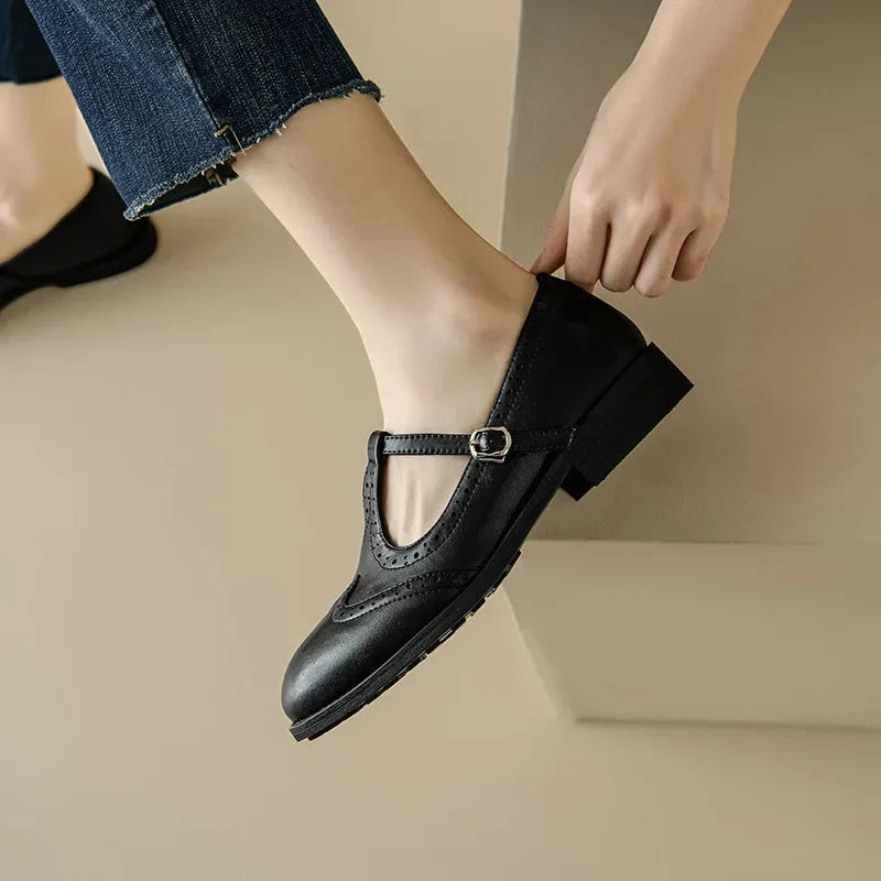 Vintage-inspired brown T-Strap Mary Jane shoes with brogue detailing, comfortable low block heel & adjustable buckle.