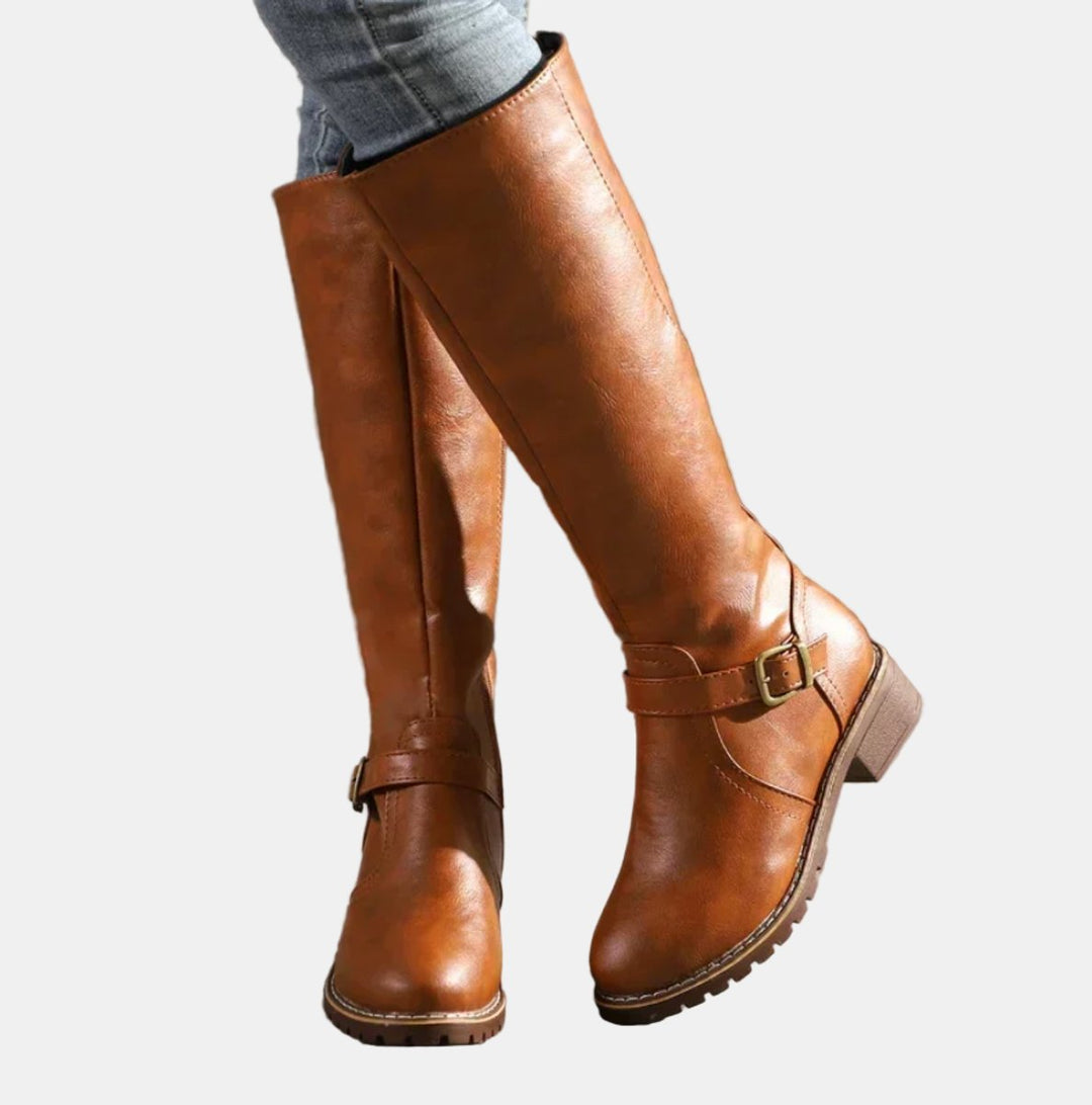 Close-up of women's buckle-strap riding boots showing detail of straps, low heel & knee-high shaft.