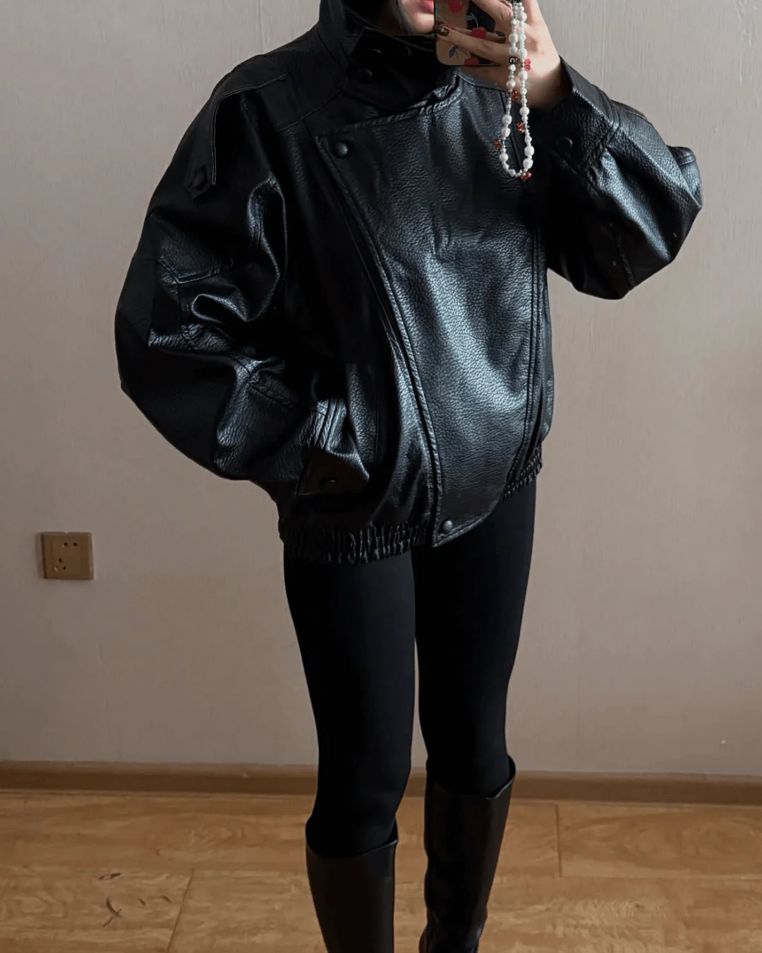 Close-up of the high neck on a women's sleek black leather jacket, modern fashion detail.