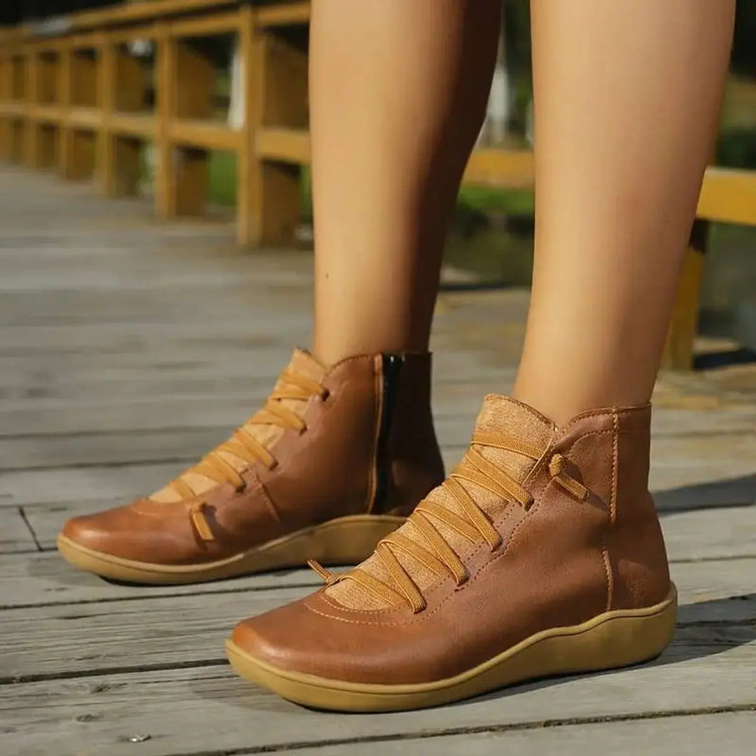 Close-up of a women's flat ankle boot showing the convenient side zip closure and lace-up detail.