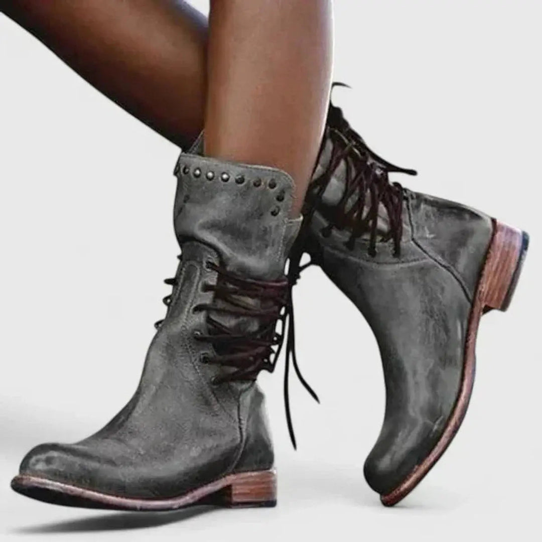 Women's black lace-up studded ankle boots with a block heel, embodying a knee-high style.