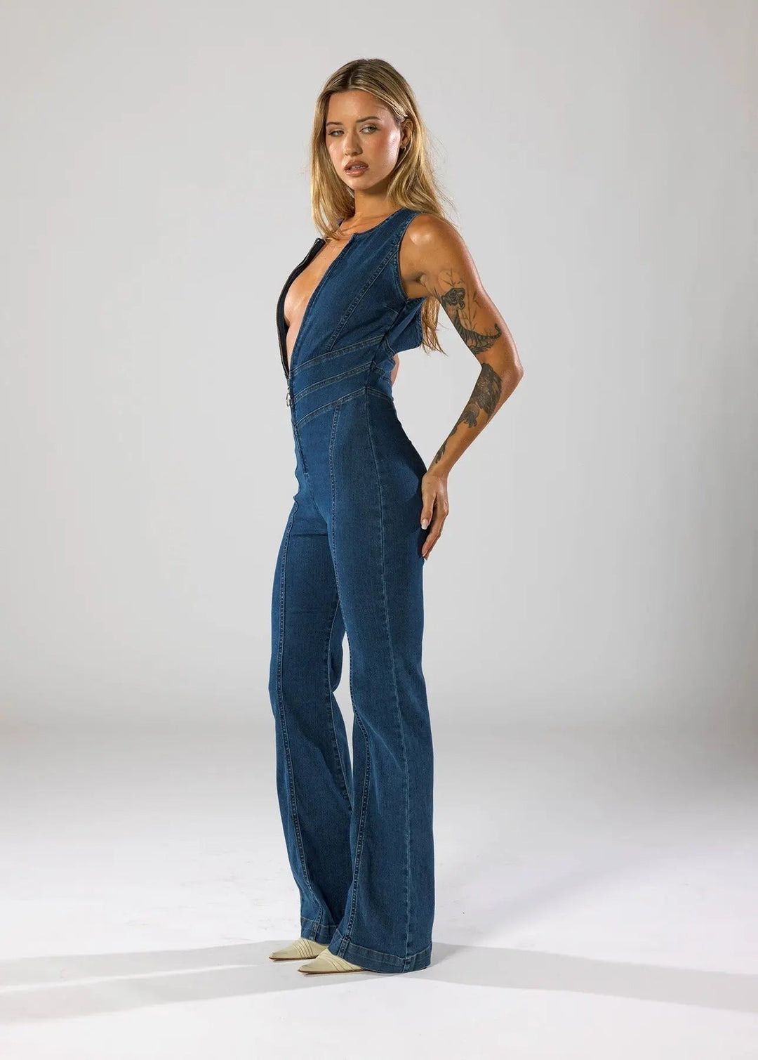 Women's fitted blue jumpsuit with a daring plunge neck and elegant flared legs. Ideal for night out & parties.