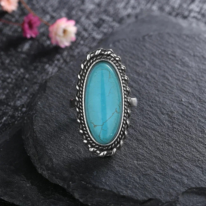 Stylish women's turquoise statement ring with an oval natural stone and braided silver design.