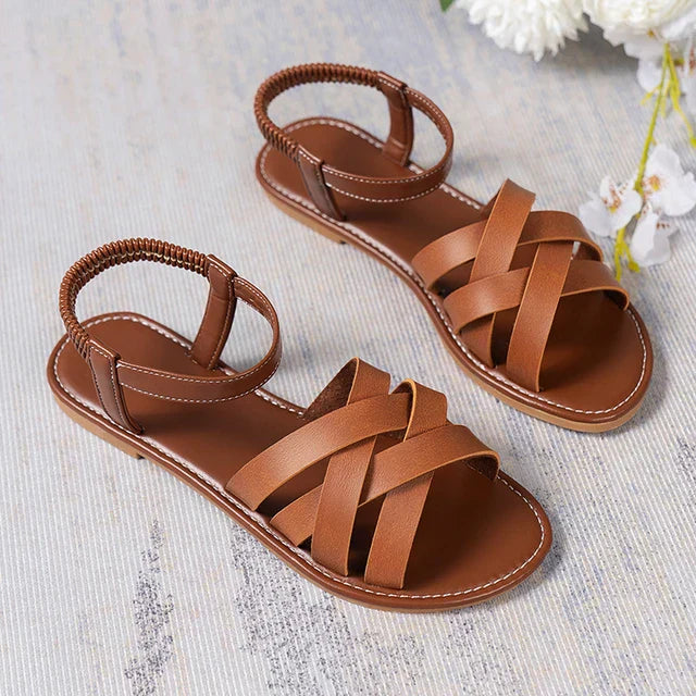 Brown women's flat sandals featuring a chic cross strap design & supportive elastic heel for ultimate summer comfort.