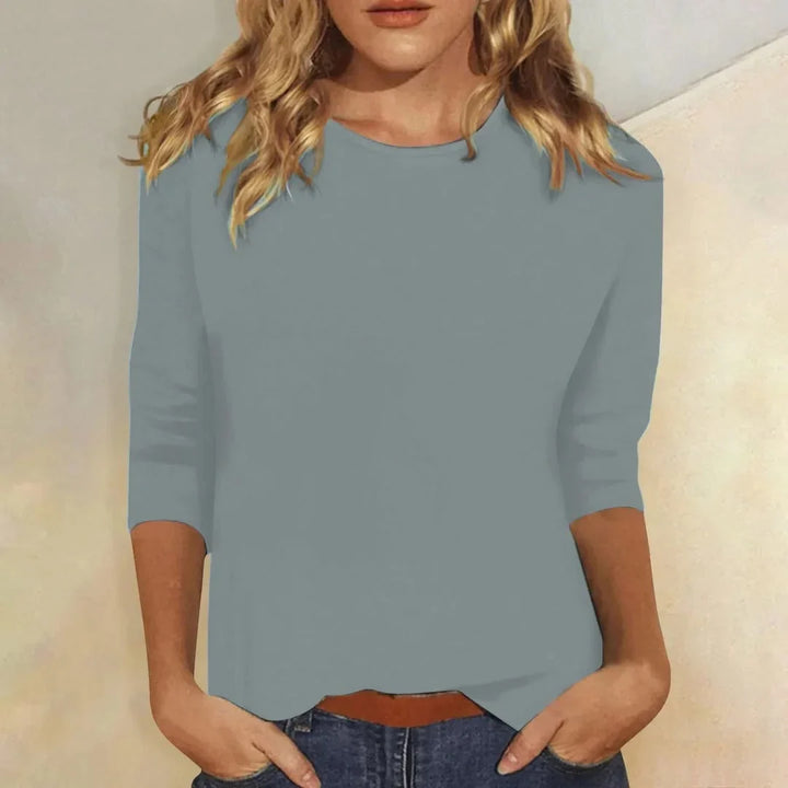 Woman models a comfortable 3/4 sleeve crew neck top, essential for versatile layering & everyday wear.