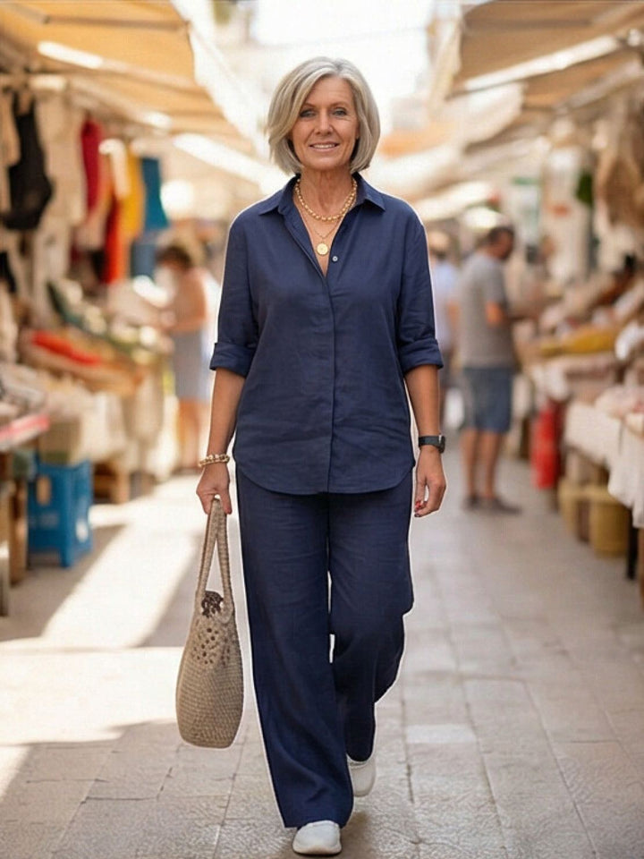 Woman sitting, dressed in a versatile two-piece lounge set: button-down top & wide-leg bottoms.