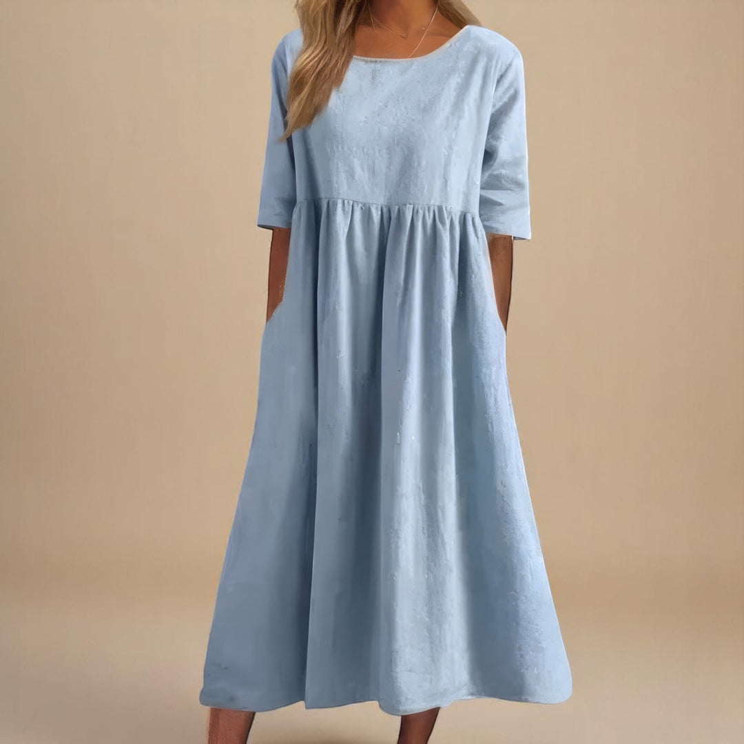 Woman models a versatile mid-sleeve comfort dress, featuring a classic round neck and handy pockets for summer.