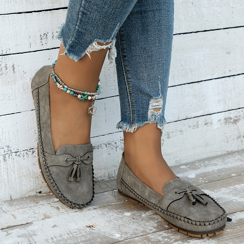 A pair of women's classic tassel loafers, showing the comfortable fit of these closed-toe slip-on flats.