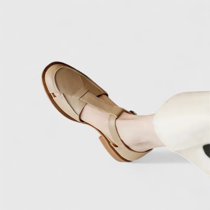 Brown closed-toe T-strap sandals for women, featuring an adjustable strap & comfortable block heel.