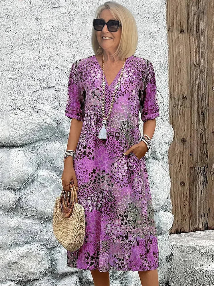 Women's colorful V-neck midi dress with abstract print, 3/4 sleeves, and functional pockets for day to night wear.