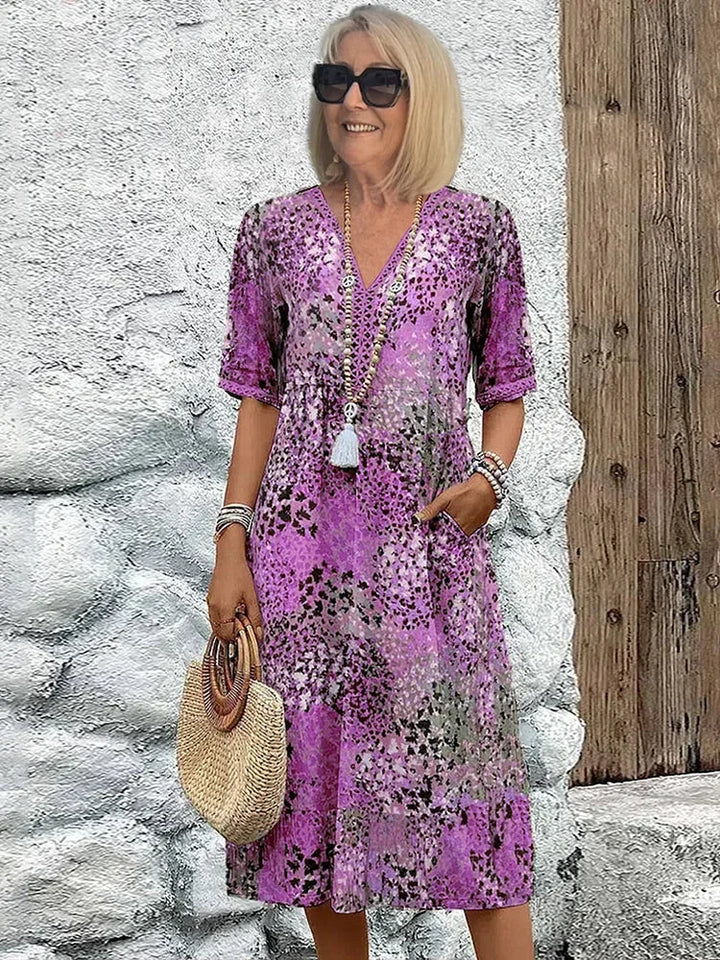 Women's colorful V-neck midi dress with abstract print, 3/4 sleeves, and functional pockets for day to night wear.