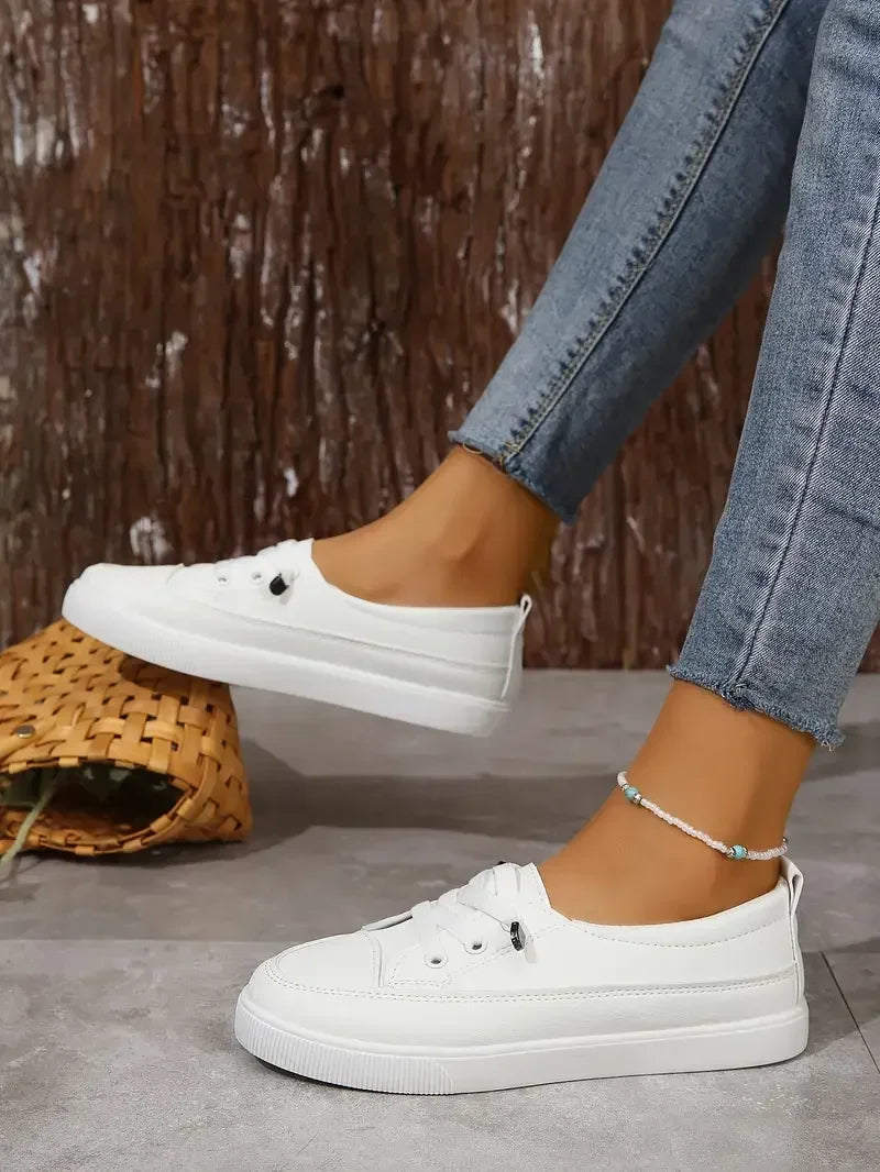 A pair of classic white women's casual flat shoes with round toe & lace-up closure. Everyday comfort footwear.