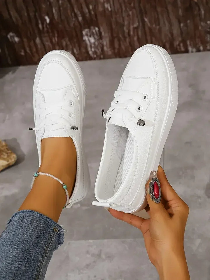 Close-up of comfortable white women's casual flats. Features round toe, lace-up design, and durable sole.