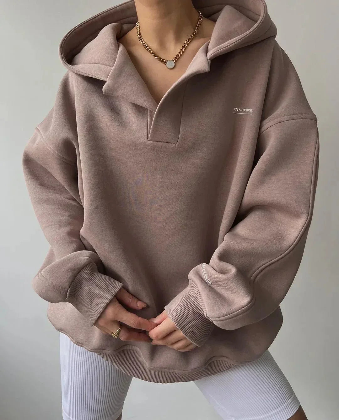 Stylish woman relaxing in a cozy oversized pullover hoodie with a trendy notch neck, ideal for everyday comfort.