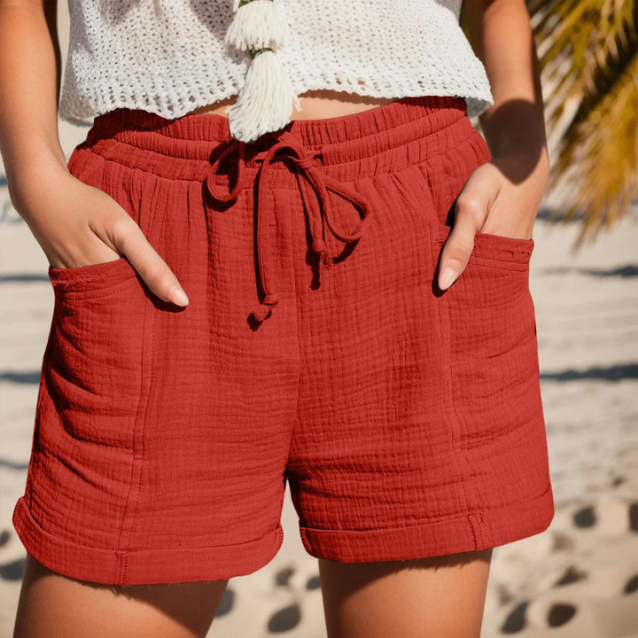 Close-up of crinkled texture, drawstring waist, and cuffed hem on women's casual summer shorts.