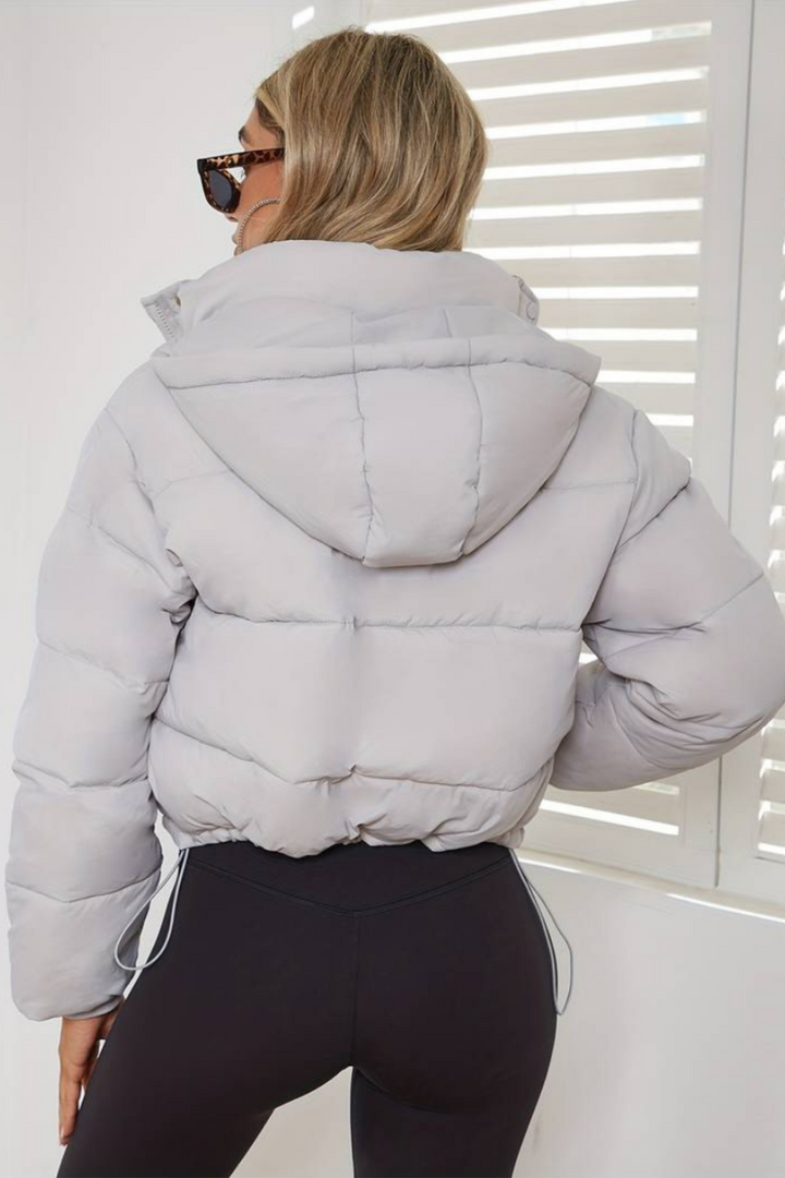 A vibrant women's cropped hooded puffer jacket, showcasing its lightweight design.