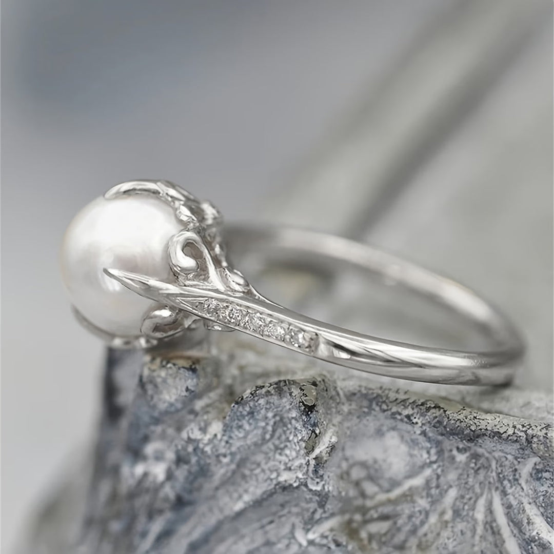 Close-up of a women's delicate ring showcasing a radiant pearl and shimmering crystal accents, modern design.