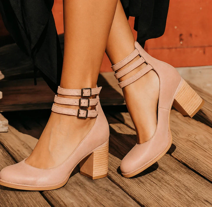 Detailed view of buckled ankle straps on women's distressed block heel sandals. Fashionable summer shoes.