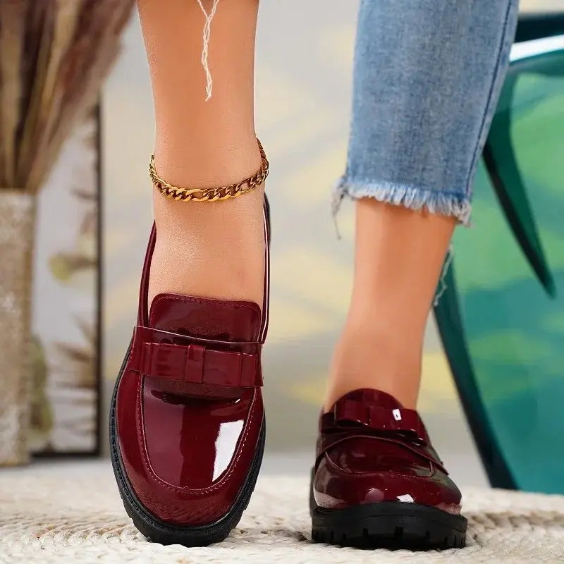 Stylish burgundy patent leather orthopedic loafers for women, featuring a chic bow and comfortable lug sole.